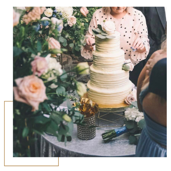 Tall white tiered cake on a decorated table with pastel flowers at a celebration