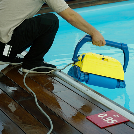 A man is holding a robotic pool cleaner