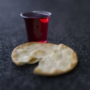 Broken cracker beside a small red cup on a dark surface