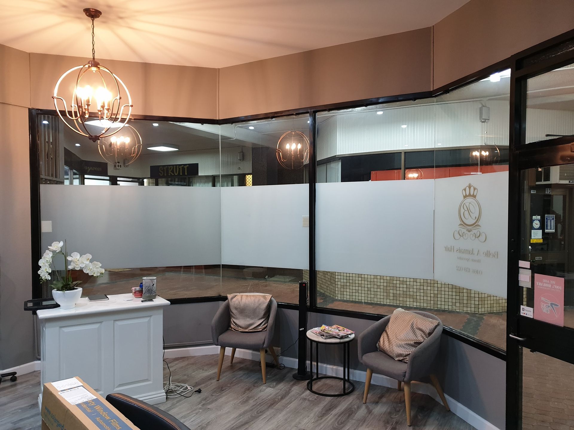 A Modern Reception Area Featuring a White Desk, Two Grey Chairs With Pillows — Shmick Tinting & Vinyl in North Hobart, TAS