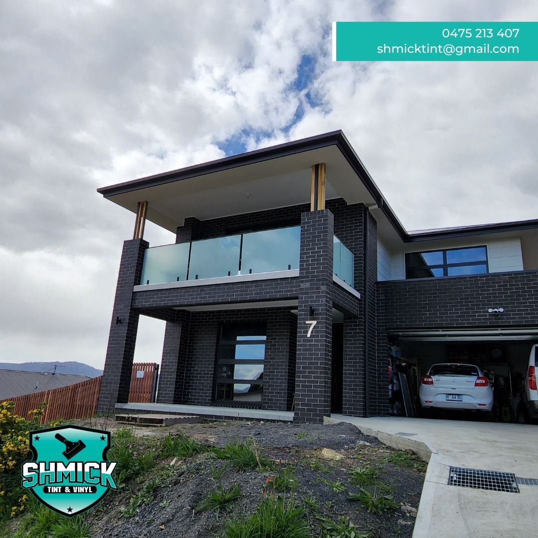 A Two-story Dark Brick Home With a Glass Balcony — Shmick Tinting & Vinyl in North Hobart, TAS