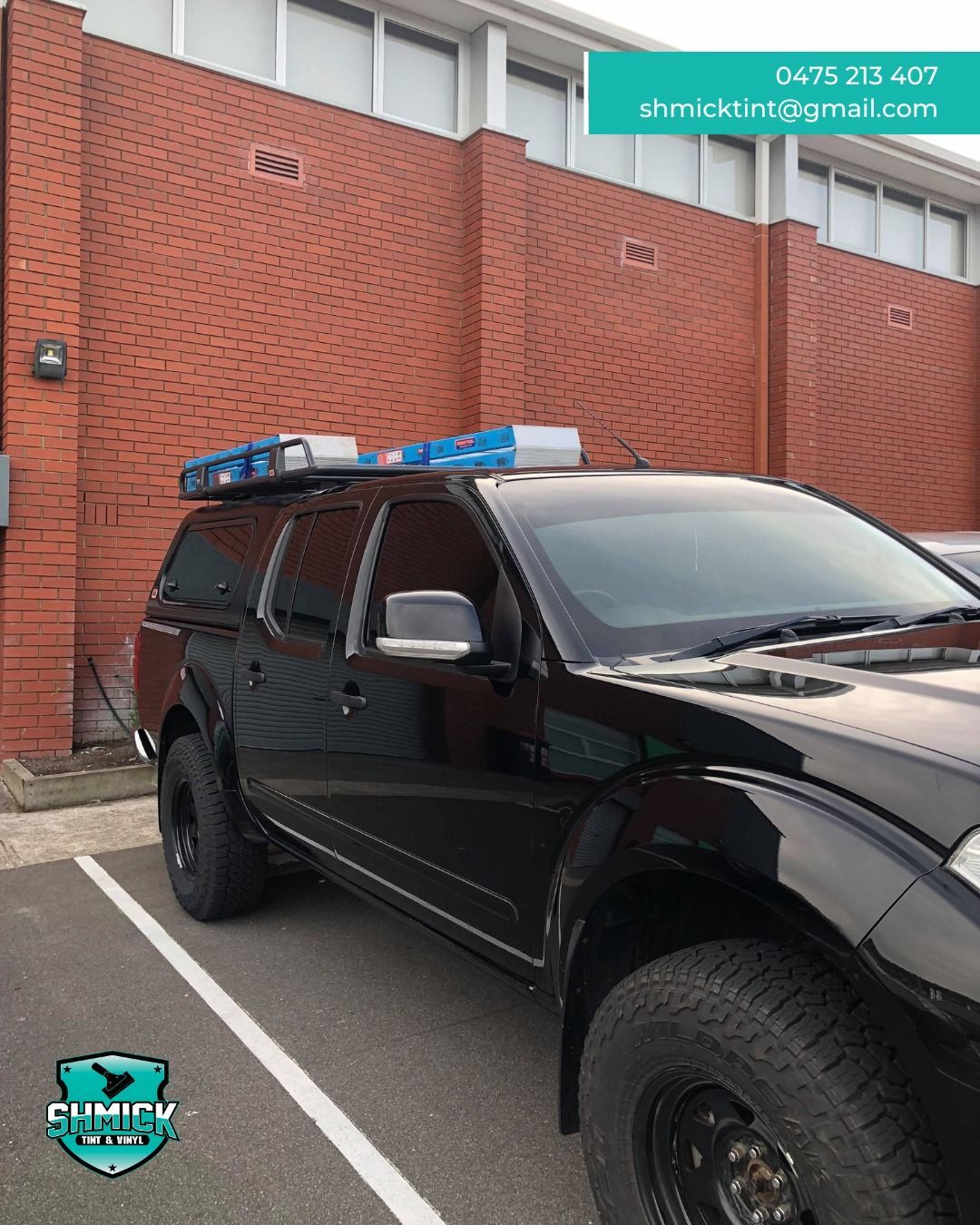 Gray building entrance with glass double doors, potted plants, and a turquoise vehicle reflected in the windows — Shmick Tinting & Vinyl in North Hobart, TAS