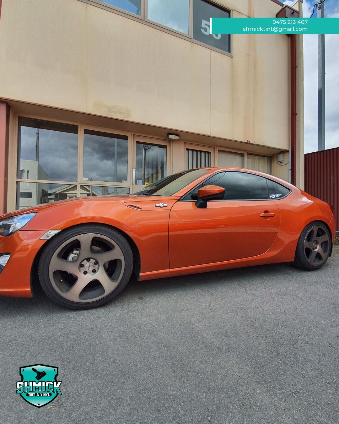 Orange Coupe Parked on Asphalt in Front of a Building With Large Glass Windows — Shmick Tinting & Vinyl in North Hobart, TAS