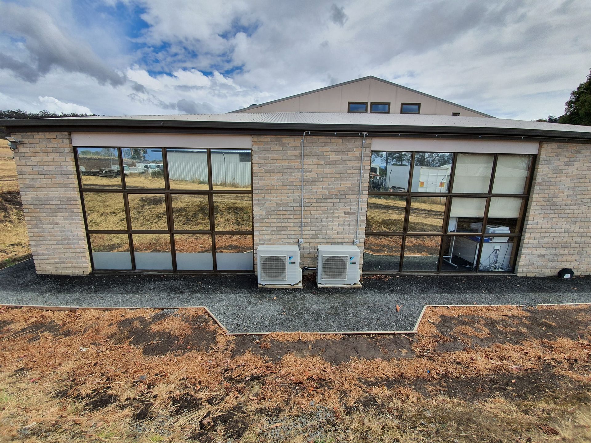 Exterior View of a Light-coloured Brick Building With Two Large Mirrored Windows — Shmick Tinting & Vinyl in North Hobart, TAS