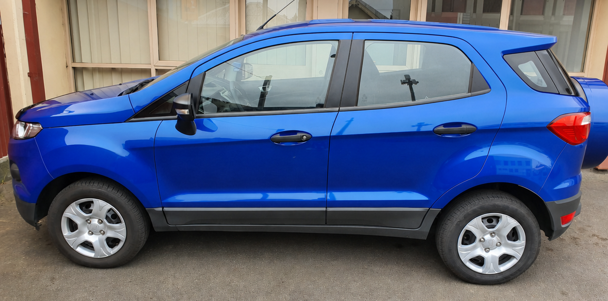 Blue compact SUV in side view, parked on a dirt surface.