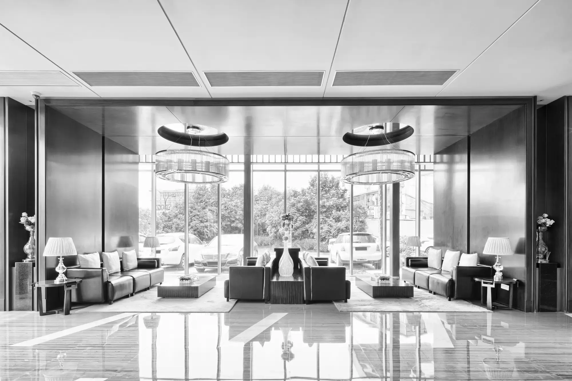 Elegant lobby with symmetrical seating, large windows, and hanging light fixtures.