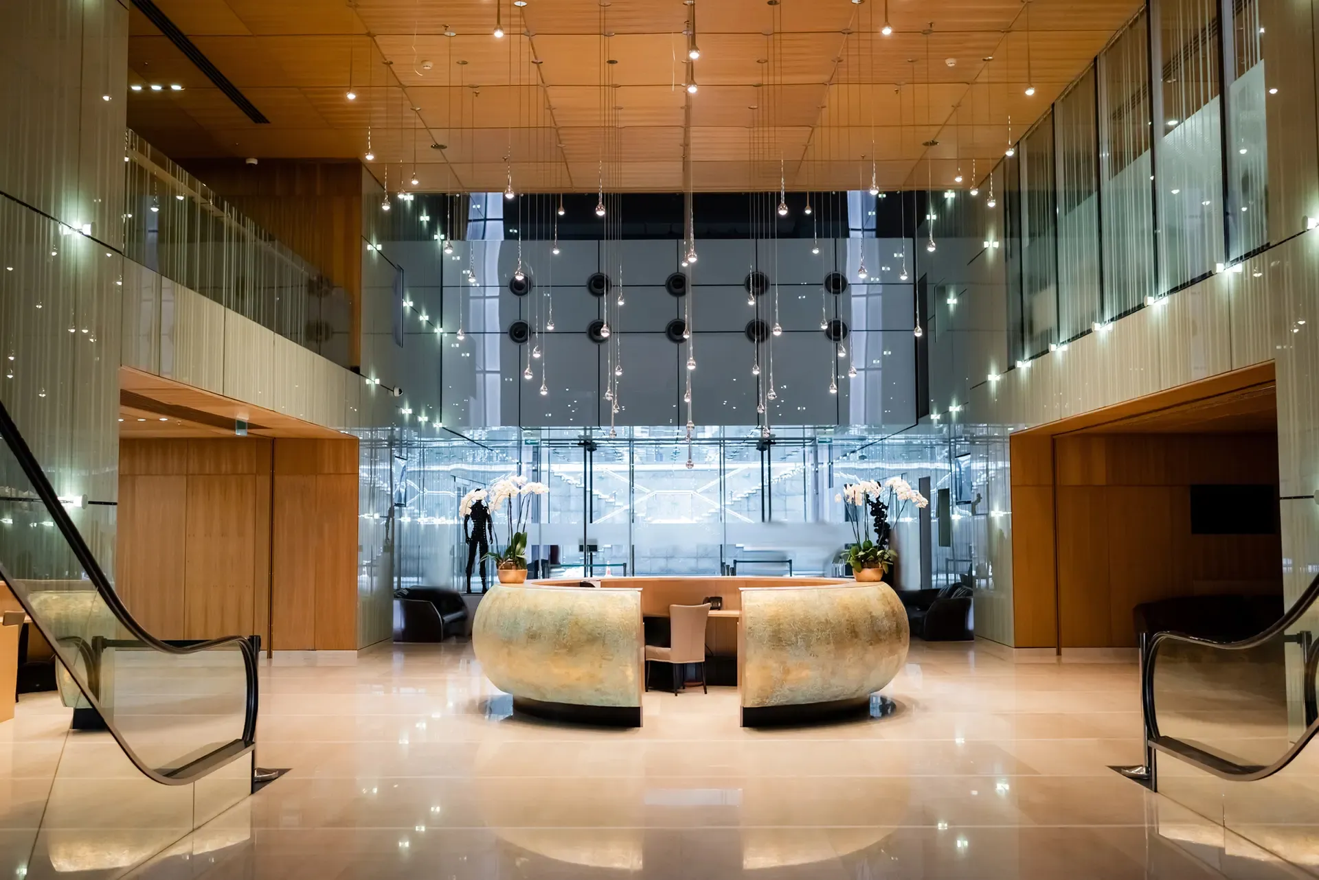 Modern lobby with a reception desk, glass walls, and wooden accents.