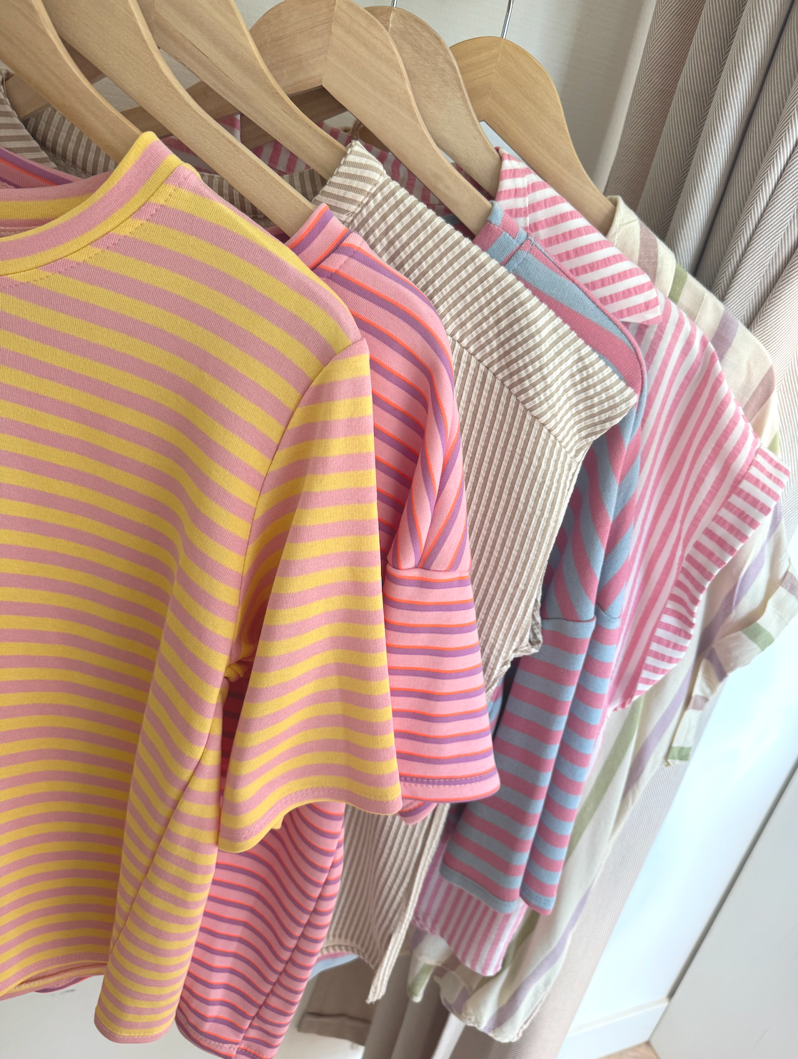Nieuwe kleurrijke gestreepte dames tops op kledinghangers in de winkel