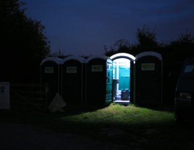 Portable toilet set up outdoors with surrounding natural light for an event restroom area