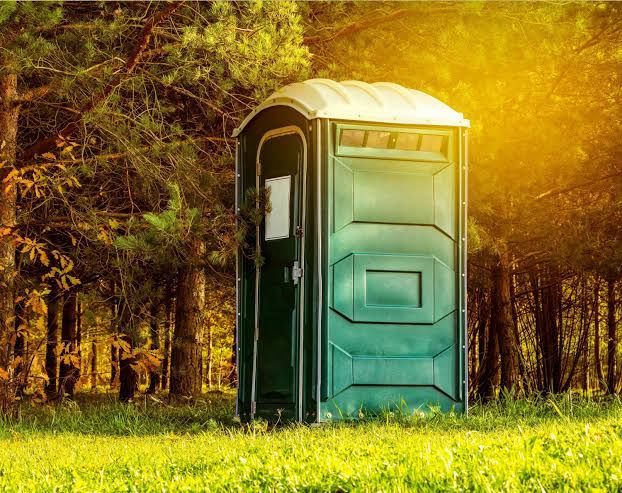 Portable toilet set up outdoors with surrounding natural light for an event restroom area