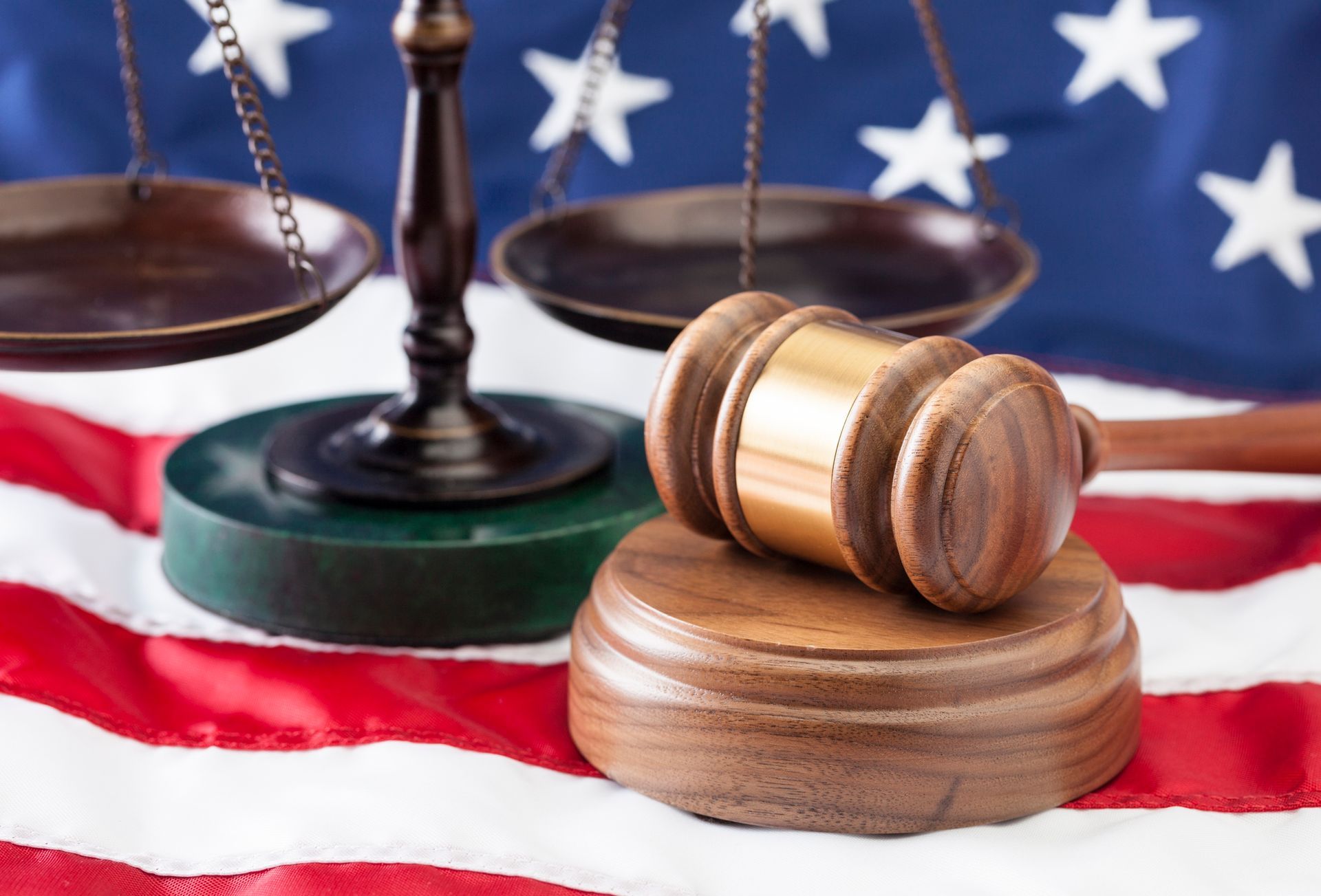 A wooden gavel and justice balance on the American flag.