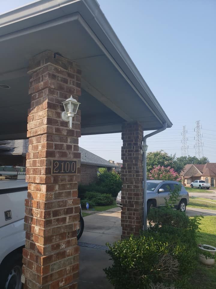 Brick house porch with hanging lantern and address plaque, driveway, and parked cars under a cloudy sky