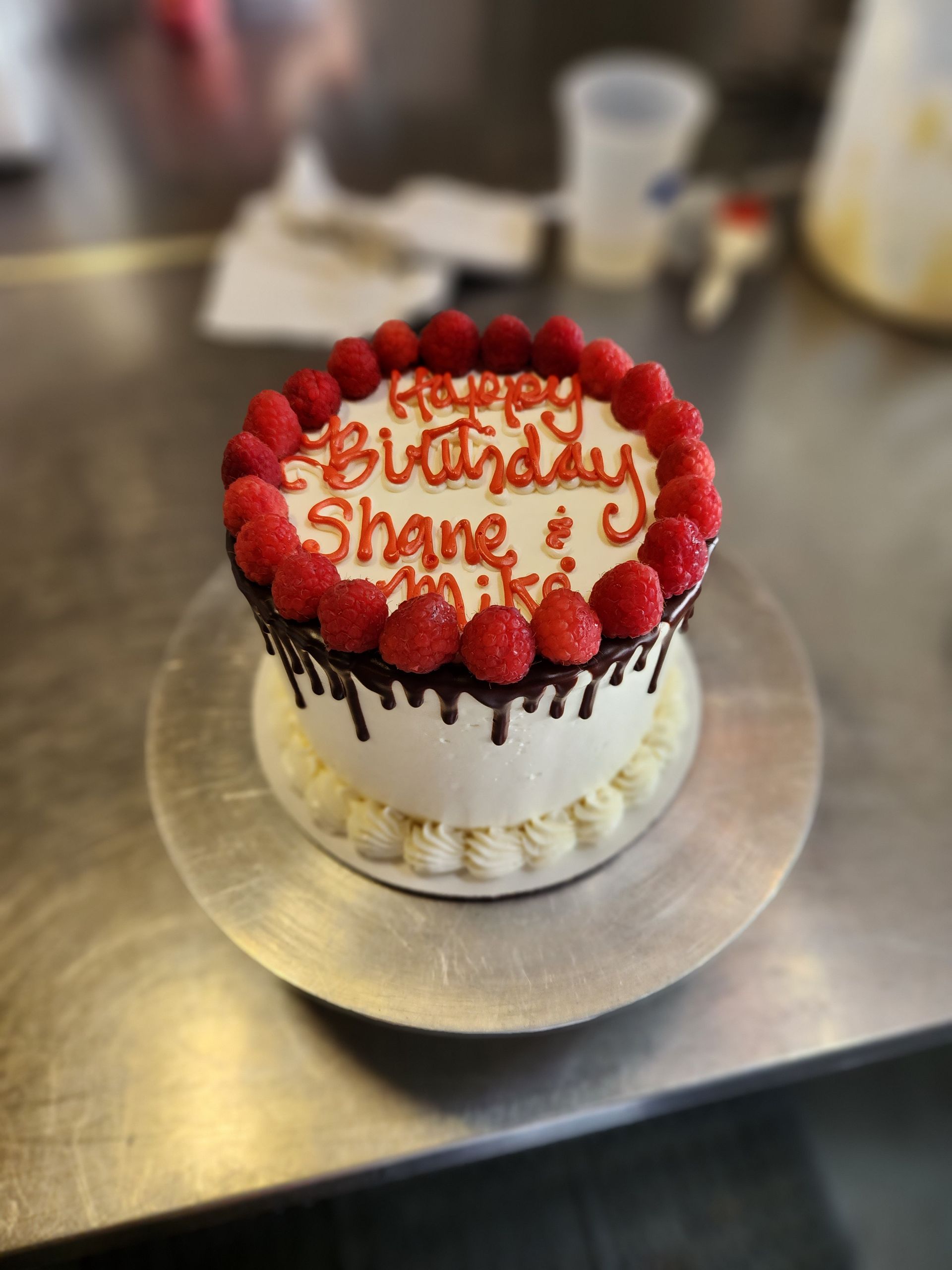 A birthday cake for shane and mike with raspberries on top