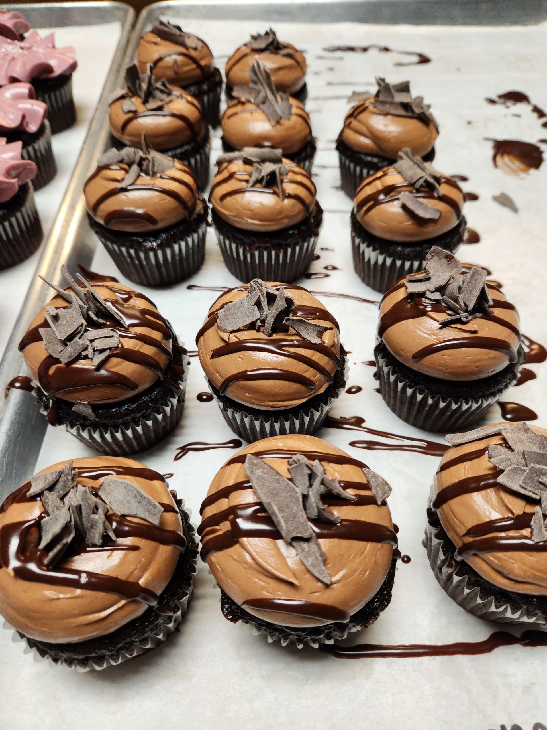 A tray of chocolate cupcakes with chocolate shavings on top