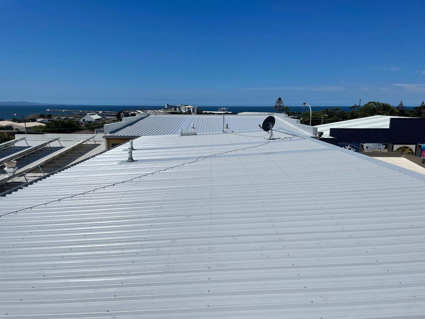 A White Roof With A View Of The Ocean On A Sunny Day — Elevated Roofing Systems Pty Ltd In Barrack Heights, NSW