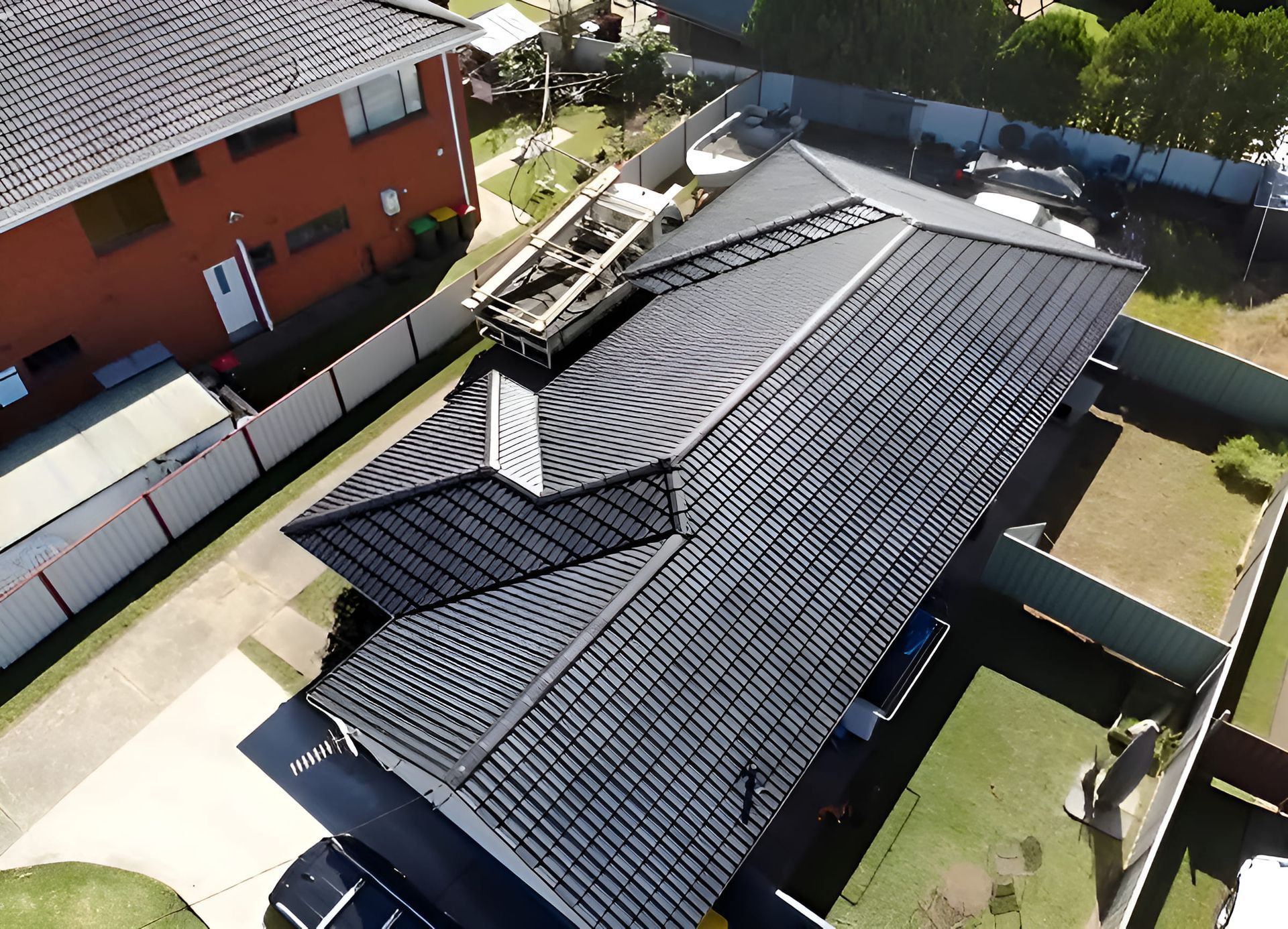 An Aerial View of a House with a brand new black roof in Wollongong. Surrounded By Trees And Grass