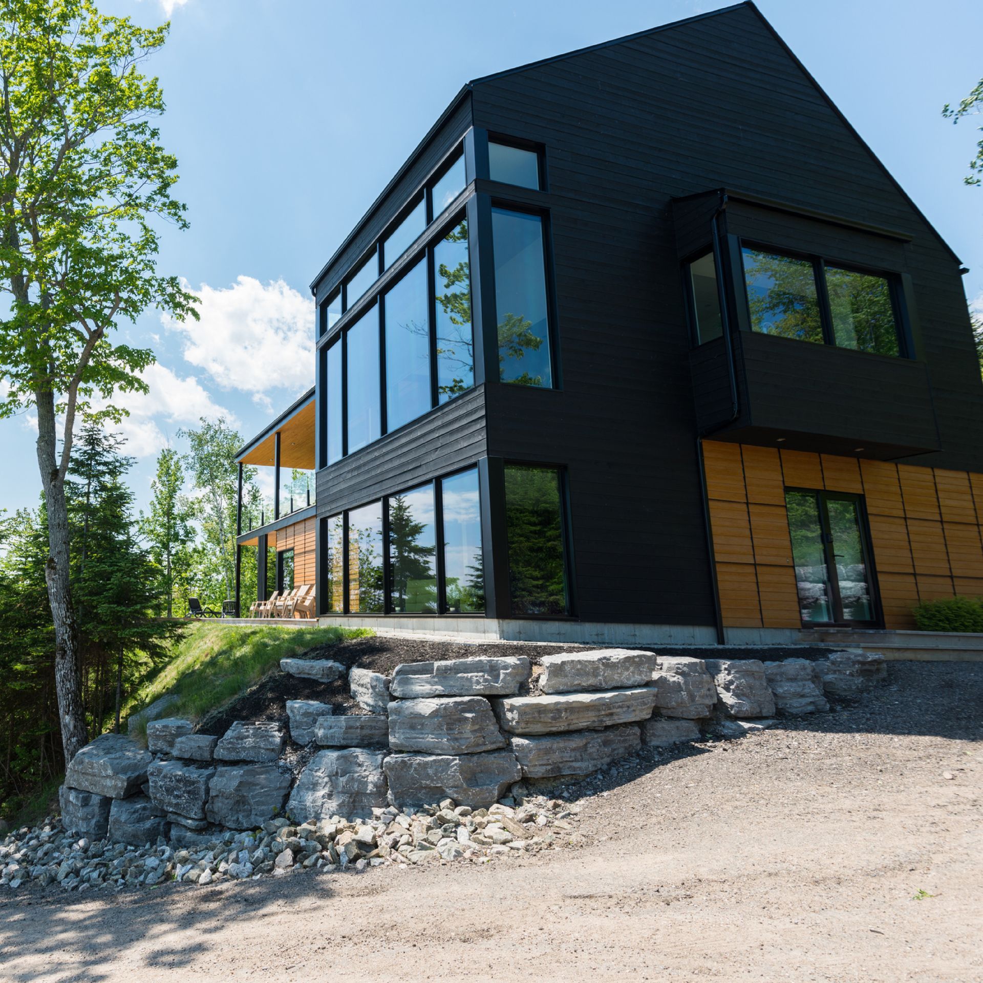Modern black house with large windows on a rocky hillside surrounded by trees