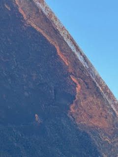 Close-up of a rocky cliff face with blue and reddish-brown textures.