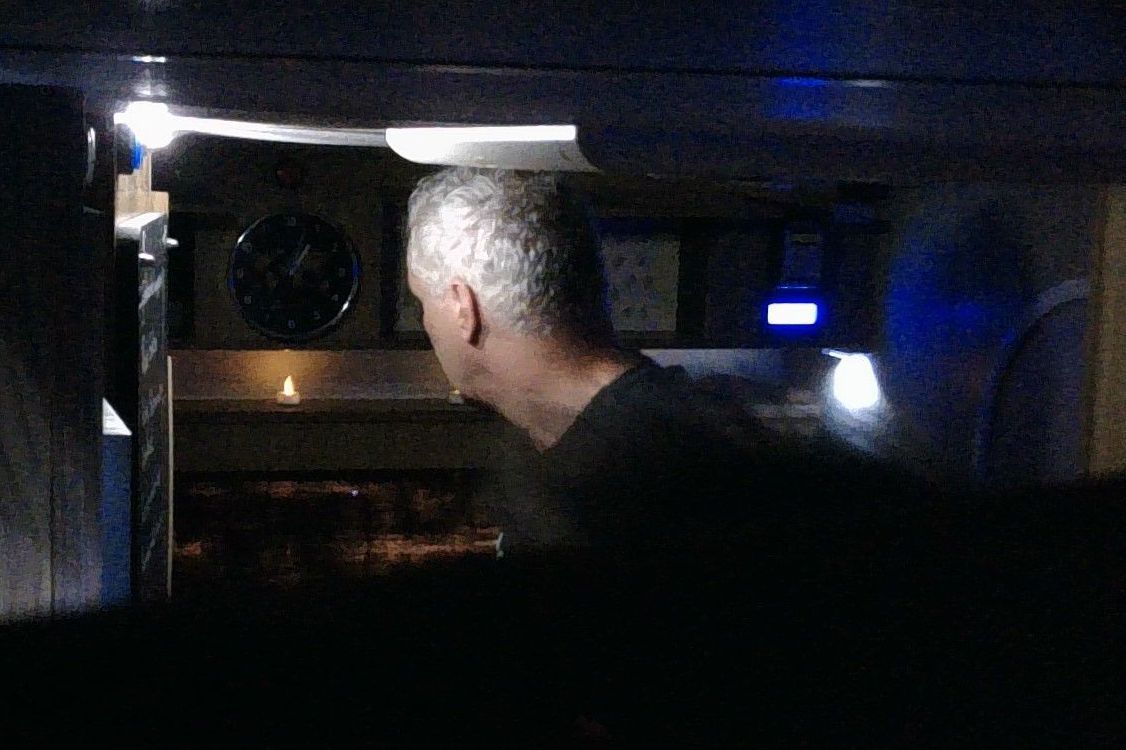 Een man kijkt in een commerciële oven, die van binnenuit verlicht is, in een schemerige keuken.