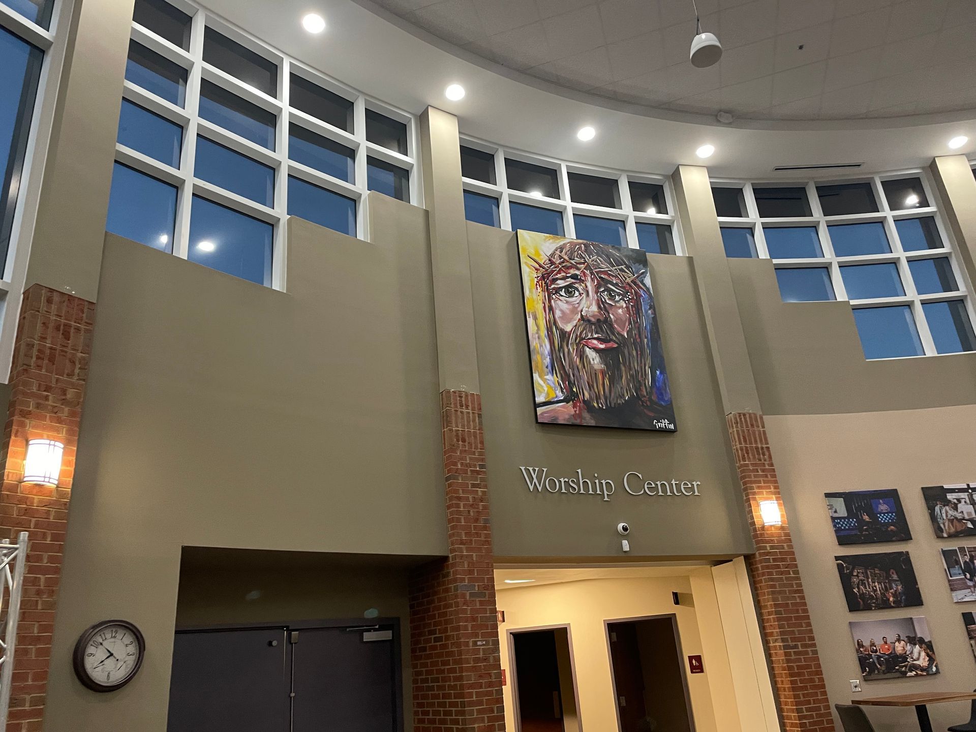 Lobby with tall windows, a colorful portrait, clock, and doorway under a curved ceiling