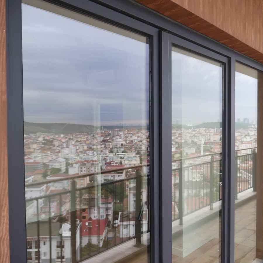Balcony view through glass doors over a dense cityscape under a cloudy sky