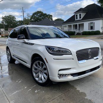 White Lincoln SUV parked in a driveway in front of a suburban house