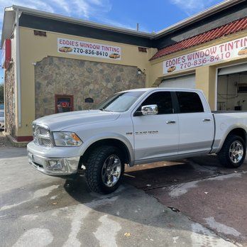 Silver pickup truck parked outside Eddie's Window Tinting shop on a sunny day.