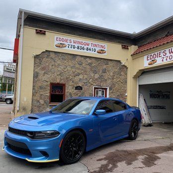 Blue sports car parked outside Eddie’s Window Tinting shop