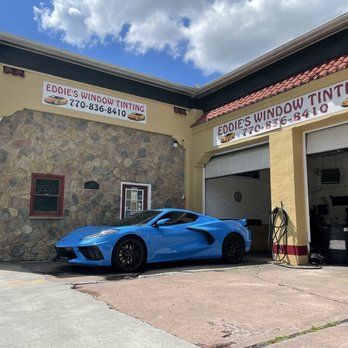 Blue sports car outside Eddie’s Window Tint shop under a sunny sky