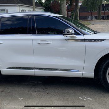 White Lincoln Aviator SUV parked on a street, side view with tinted windows and chrome trim