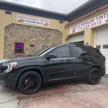Black SUV parked outside Eddie’s Window Tinting storefront with an open sign.