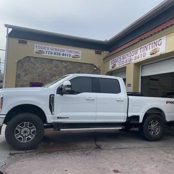 White pickup truck parked outside Eddies Window Tinting shop building