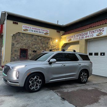 Silver SUV parked outside Eddies Window Tinting storefront at dusk