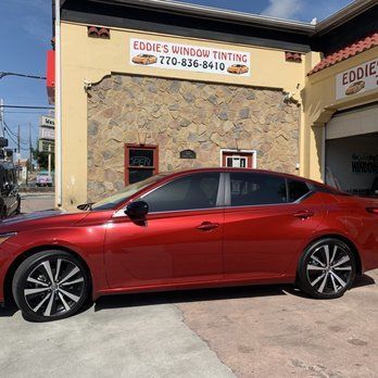 Red sedan parked outside Eddie’s Window Tinting storefront on a sunny day