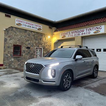 Silver SUV parked outside Eddie’s Window Tinting storefront at dusk