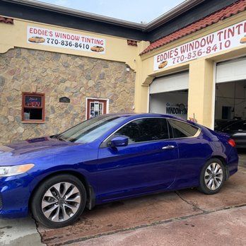 Blue sedan parked outside Eddie's Window Tinting shop under a covered entrance.