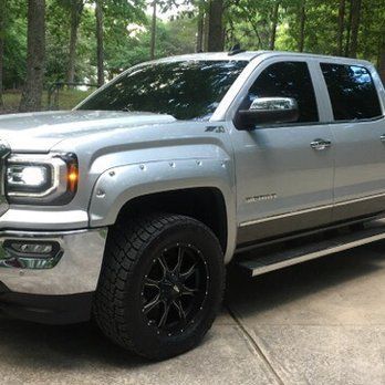 Silver pickup truck parked on a driveway in a wooded area