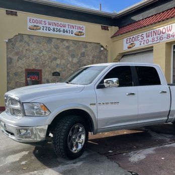 White pickup truck parked outside Eddie’s Window Tinting shop on a sunny day