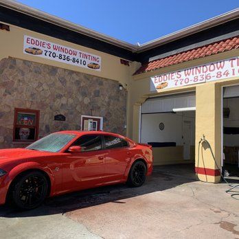 Red sports car outside Eddie’s Window Tinting shop on a sunny day