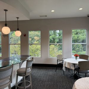 Bright dining room with large windows, round tables, and pendant lights overlooking greenery