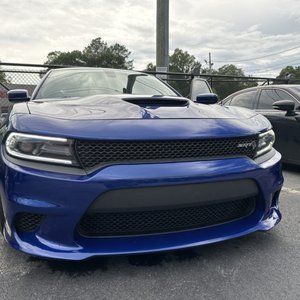 Blue Dodge Charger parked front-facing in a lot, with a hood scoop and black grille.