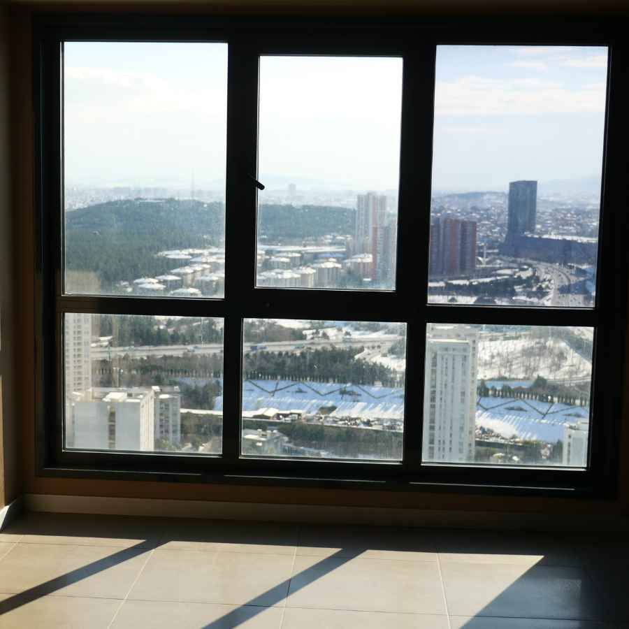 Floor-to-ceiling window with a city skyline view over a sunlit room