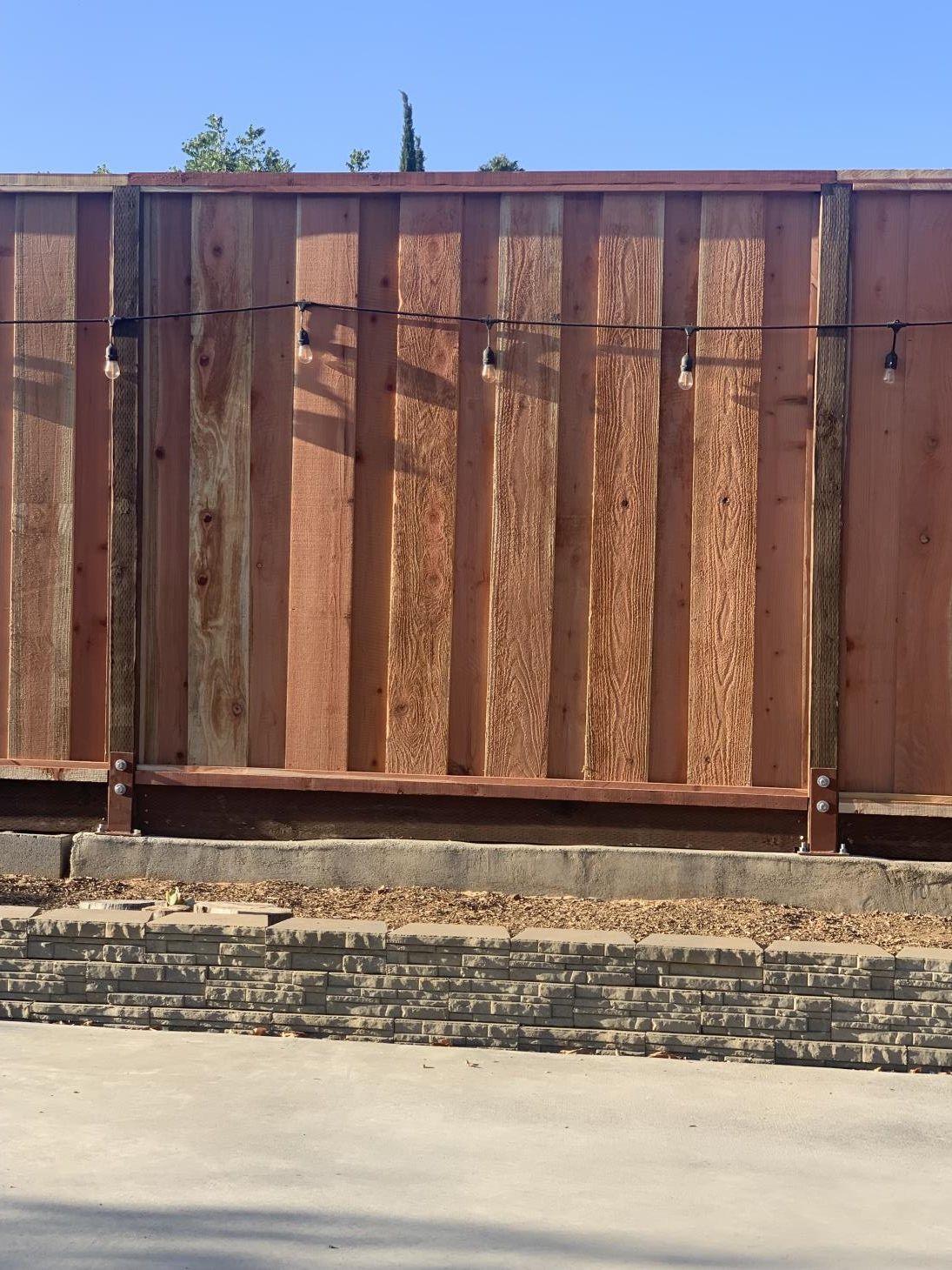 Stack of vertical slat replacement fence panels in a residential backyard, prepared for installation.