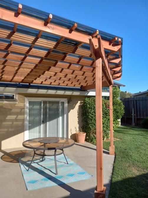 A patio with a pergola and a table underneath it
