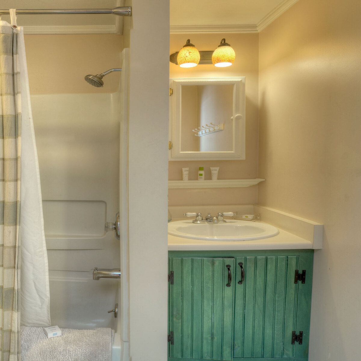 A standard bathroom with a shower, sink, and green cabinet