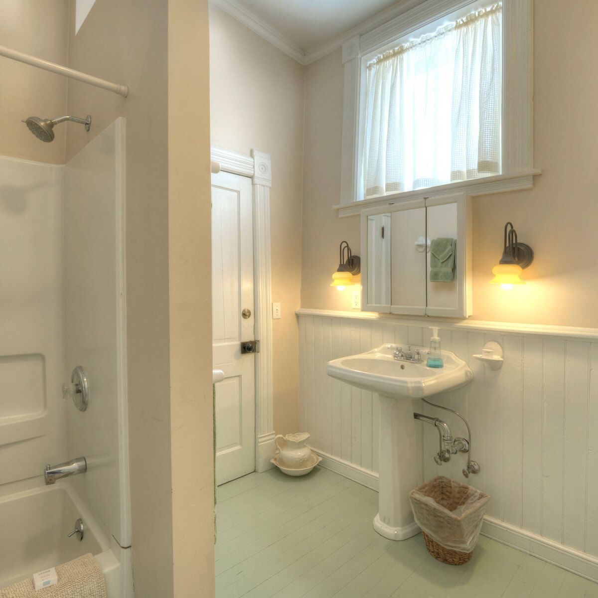 A clean bathroom with a white sink, beige walls, green floor, and shower