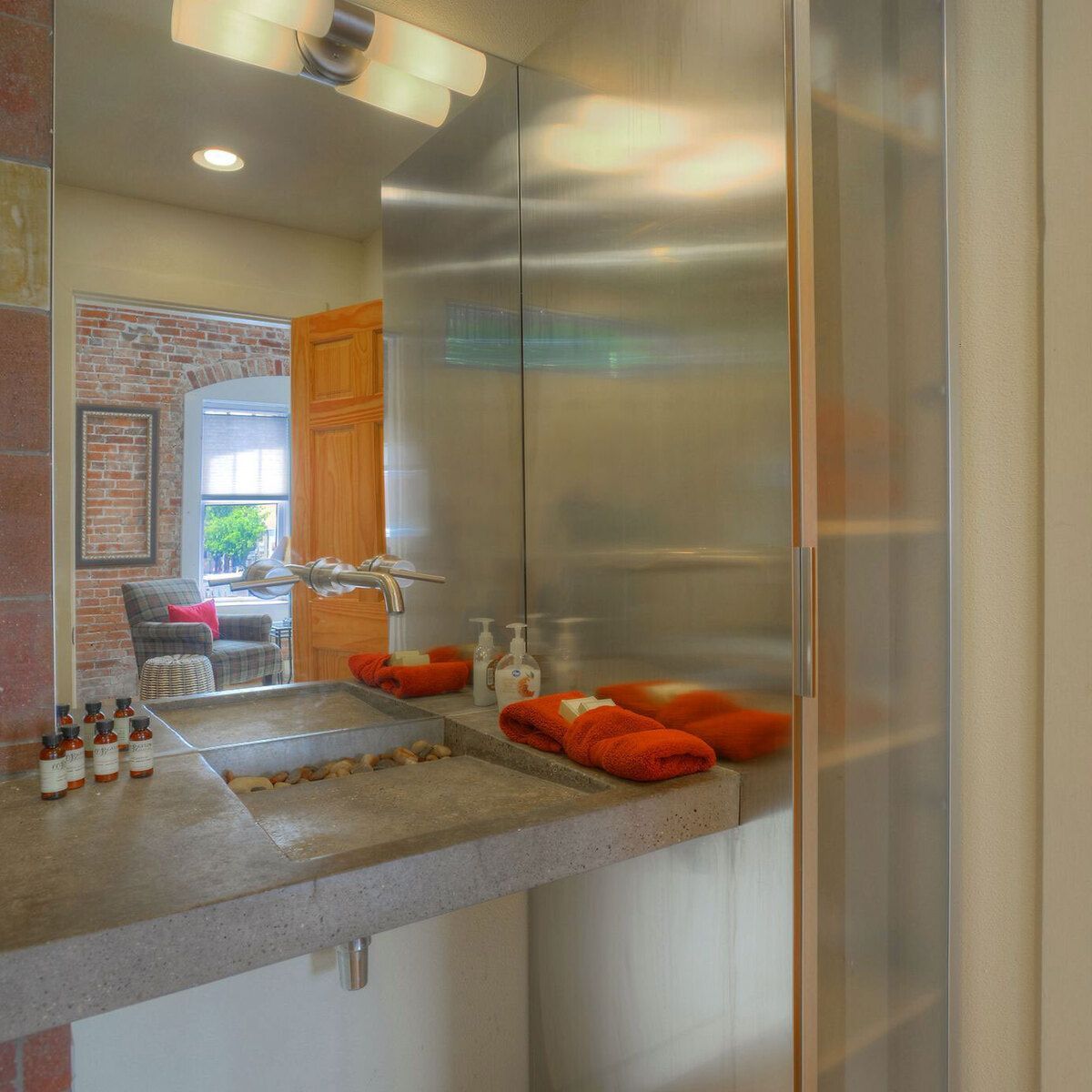 A bathroom sink area with a concrete countertop, stone sink, and red towels.