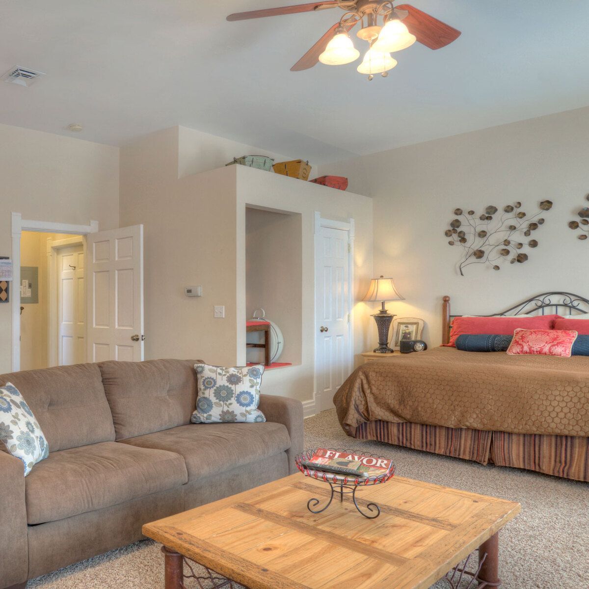A guest room with a sofa, coffee table, bed, and ceiling fan.