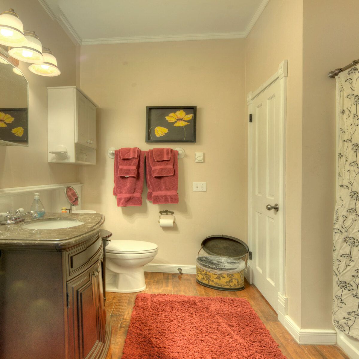 A standard hotel bathroom with a marble countertop, wooden cabinet, white toilet, and pink towels.