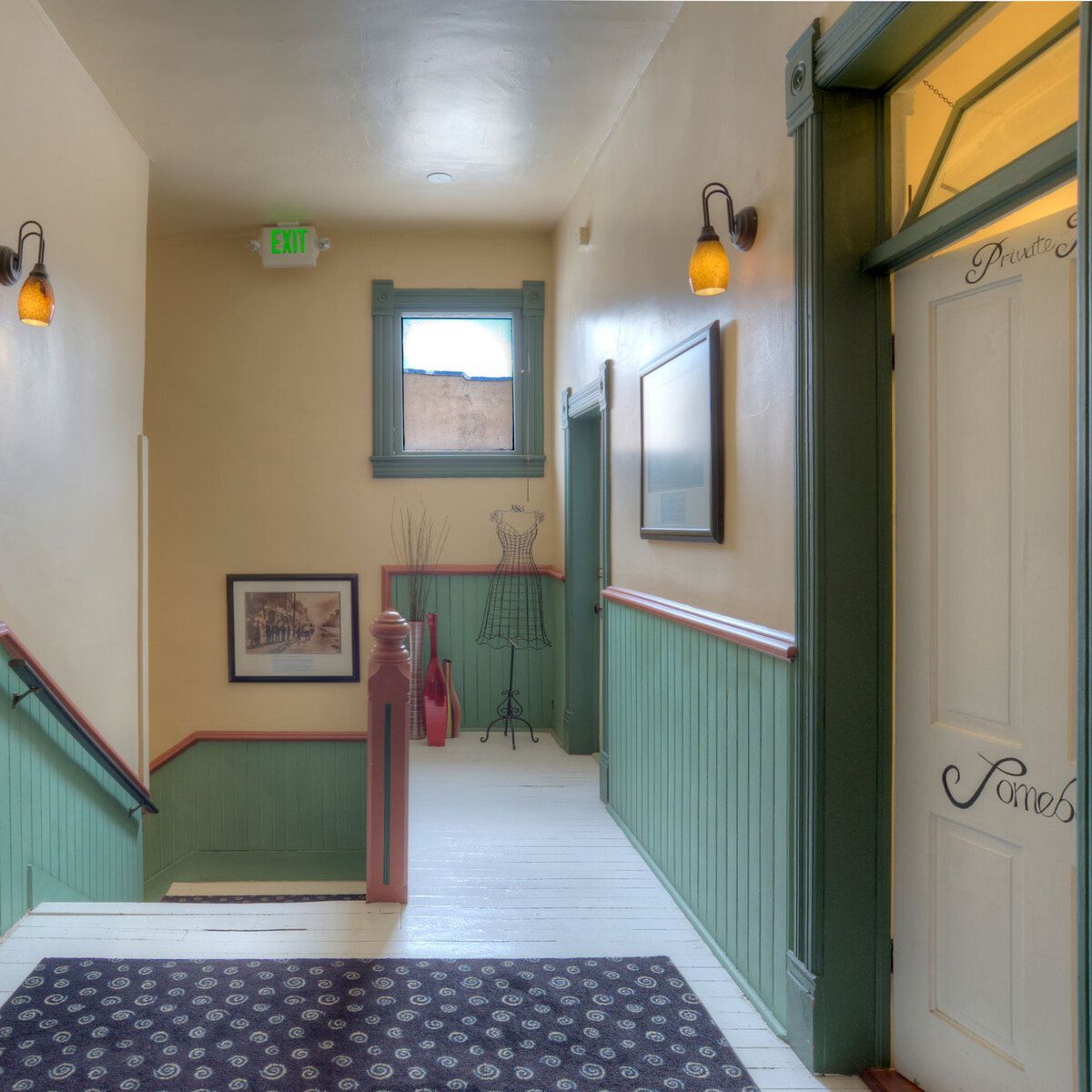 A hallway with green trim, a white door, and a blue carpet.